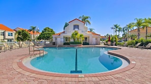 A swimming pool with a brick border, surrounded by lounge chairs and palm trees. - Updated 2BR/2BA Isla Del Sol Condo with Golf Course Views & Pool Near St. Pete Beach (Isla Del Sol)