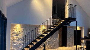 Een modern interieur met een trap, een structuurwand en een minimalistisch ontwerp.