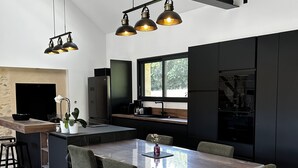 Een moderne keuken met een centraal eiland, barstoelen en hanglampen.