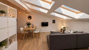 A modern loft with skylights, a dining area, a sofa, and a TV. - Skylight Loft in City Center with AC (Kraków)