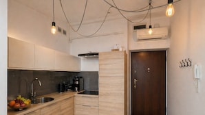 A modern kitchen with wooden cabinets, a stainless steel sink, and a built-in oven. There is a wooden door and a wall-mounted phone. - Skylight Loft in City Center with AC (Kraków)