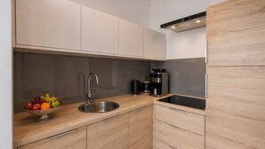 A modern kitchen with a stainless steel sink, a coffee maker, and a fruit bowl on the counter. - Skylight Loft in City Center with AC (Kraków)