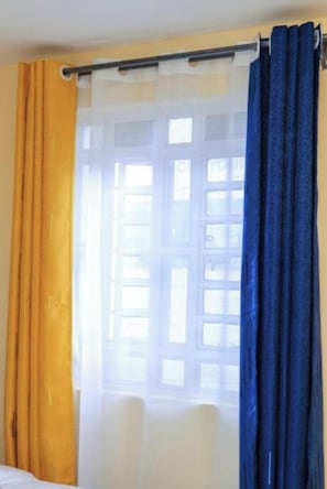 Une piĂšce avec une fenĂȘtre, une tringle Ă rideaux et un lit.