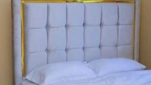 Un letto con testiera capitonata, biancheria da letto bianca e un piccolo tappeto.
