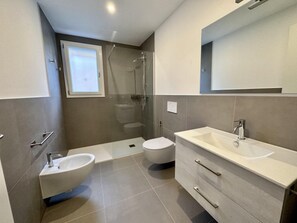A modern bathroom with a shower, toilet, sink, and mirror. - Cozy Flat With Garden and Pool (San Michele al Tagliamento)
