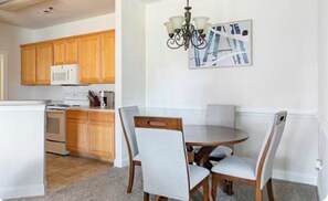 Une cuisine dotée de meubles en bois, d’un four à micro-ondes et d’un coin repas avec une table ronde et des chaises.