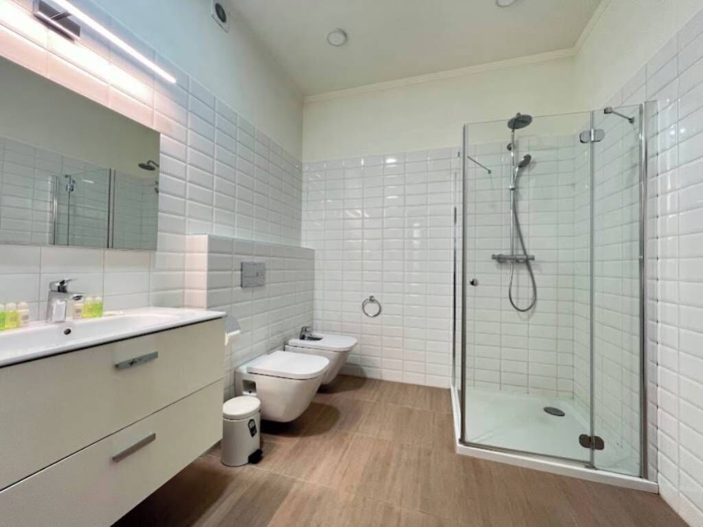 A modern bathroom with a glass-enclosed shower, a white sink, and a toilet.