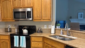 Cocina con armarios de madera, microondas, estufa y lavavajillas.