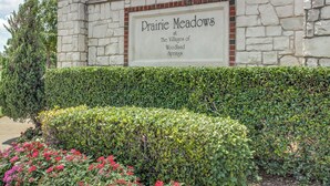 Muro de piedra con un letrero que dice 'Prairie Meadows en The Villages of Woodland Springs'.