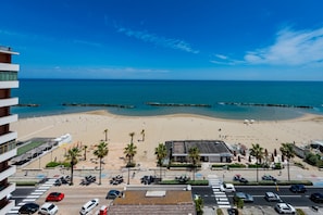 A beach view from a hotel with a parking lot and palm trees. - GuestHost - Sea View Europa Apartment (Montesilvano)