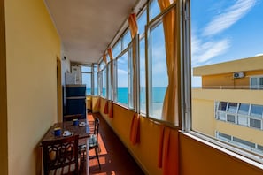 A balcony with a dining table, chairs, and curtains. - GuestHost - Sea View Europa Apartment (Montesilvano)