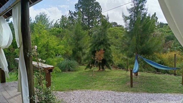 Ett trädäck med ett område täckt av grus, en hängmatta och ett picknickbord.