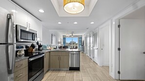 A modern kitchen with stainless steel appliances, a central island, and a view to the outside. - 2BR Bayfront Suite w/ Marina Views | Pools & Beach (Treasure Island)