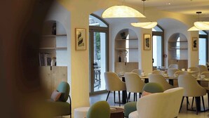 Un comedor con varias mesas y sillas, techo abovedado e iluminación colgante.
