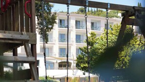 Une aire de jeux avec des balançoires et une structure d’escalade en bois.