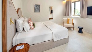 Ein Schlafzimmer mit Bett, Nachttisch, Stuhl und einem Fenster mit Vorhängen.
