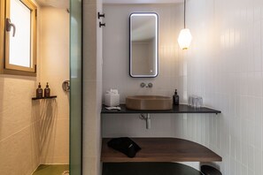 Une salle de bain moderne avec une douche à parois de verre, un lavabo beige et un miroir avec éclairage intégré.