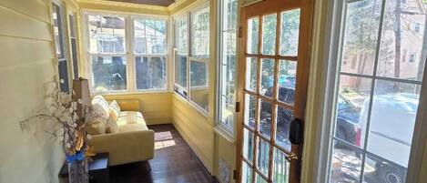 A room with a wooden ceiling, large windows, a sofa, and a bench.