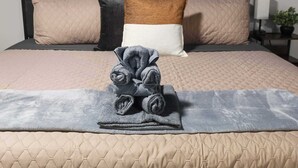 A neatly made bed with a quilted headboard, a rolled towel, and a small potted plant on the nightstand. - Family Favorite_Arcades_ KingBeds_ Sleeps 10_ BBQ (Shawnee)