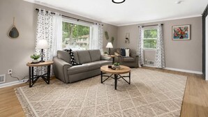 A living room with a sofa, two side tables, a coffee table, a lamp, and a painting on the wall. - Family Favorite_Arcades_ KingBeds_ Sleeps 10_ BBQ (Shawnee)