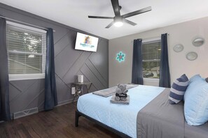A bedroom with a bed, a ceiling fan, a TV, and a small table with a lamp. - Cozy Home_Arcades_KingBeds_Sleeps 10_BBQ Grill (Shawnee)