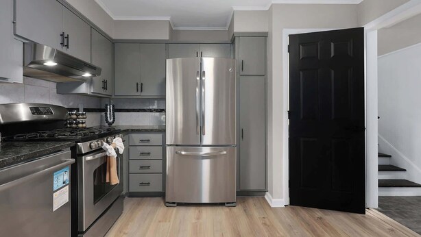 A modern kitchen with stainless steel appliances, grey cabinets, and a wooden floor. - Family Favorite_Arcades_ KingBeds_ Sleeps 10_ BBQ (Shawnee)