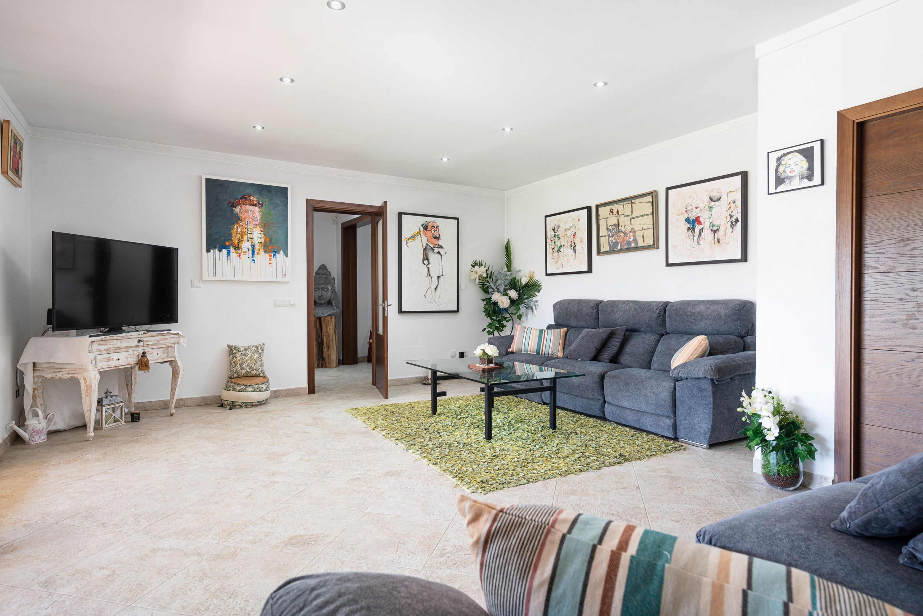 A living room with a sofa, a coffee table, a TV, and artwork on the walls.