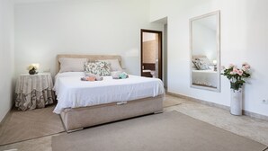 Une chambre à coucher avec un lit, des tables de chevet, un miroir et un vase de fleurs.