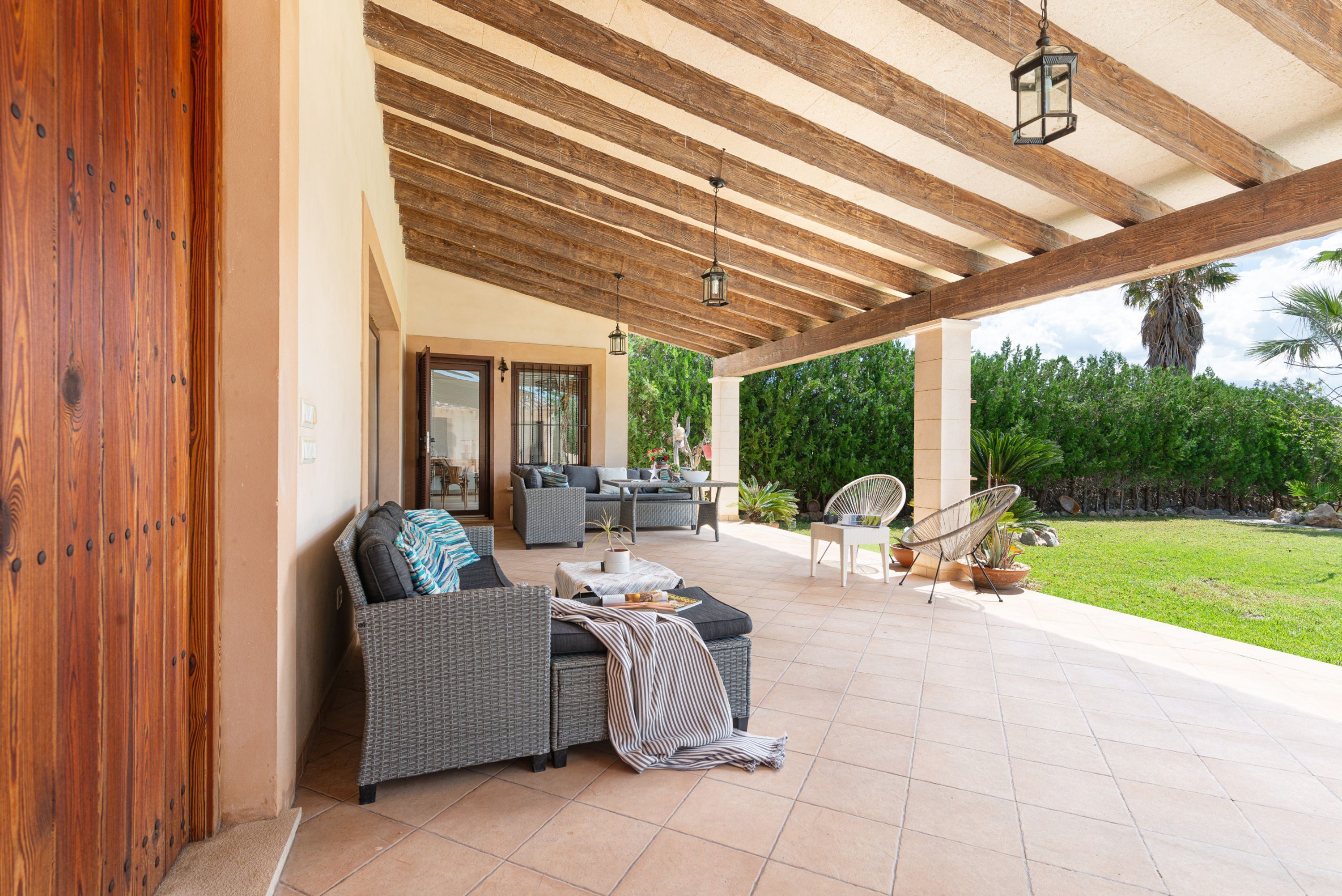 Un patio al aire libre con una zona de estar techada, una mesa de comedor y una silla de descanso.