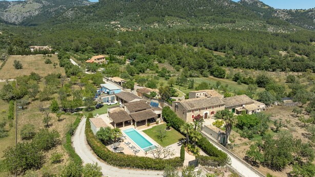 Vue aérienne d’un quartier résidentiel avec une piscine, des maisons et un paysage montagneux en arrière-plan.
