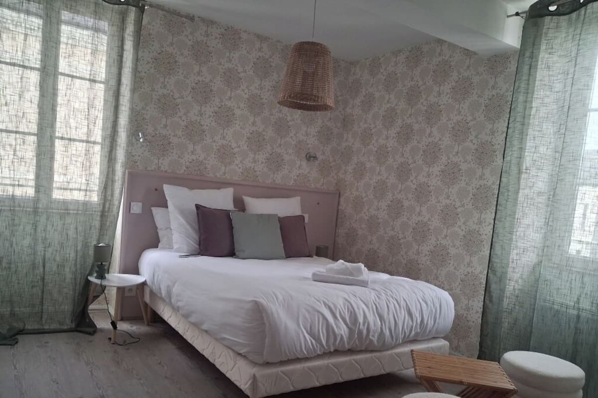 Un dormitorio con cama, mesita de noche, lámpara y una lámpara colgante.