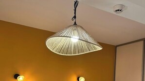 A hotel room with a bed, pillows, a folded towel, a hanging lamp, and wall sconces. - Au Bosquet Fleuri - Maison de campagne (Martizay)