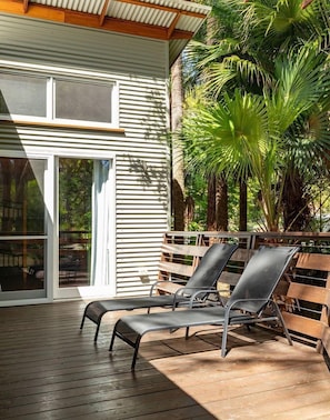 Un espacio al aire libre cubierto con dos sillones y una terraza de madera.