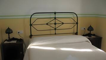 Een bed met een metalen hoofdbord, twee nachtkastjes met lampen, en een muur met een groene strook.