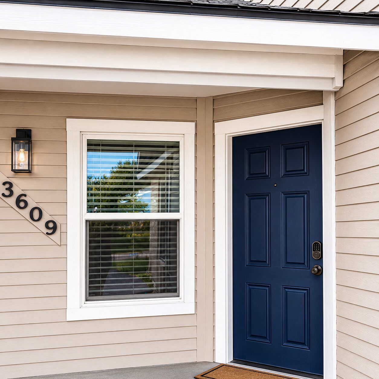 Una casa con puerta principal azul oscuro, una ventana con persianas y un buzón con el número 3609.