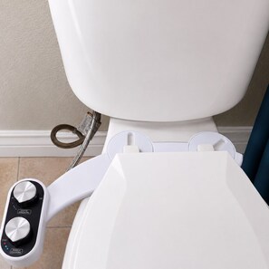 Des toilettes équipées d’un dispositif de bidet et de boutons de commande pour régler la température de l’eau et nettoyer la buse.