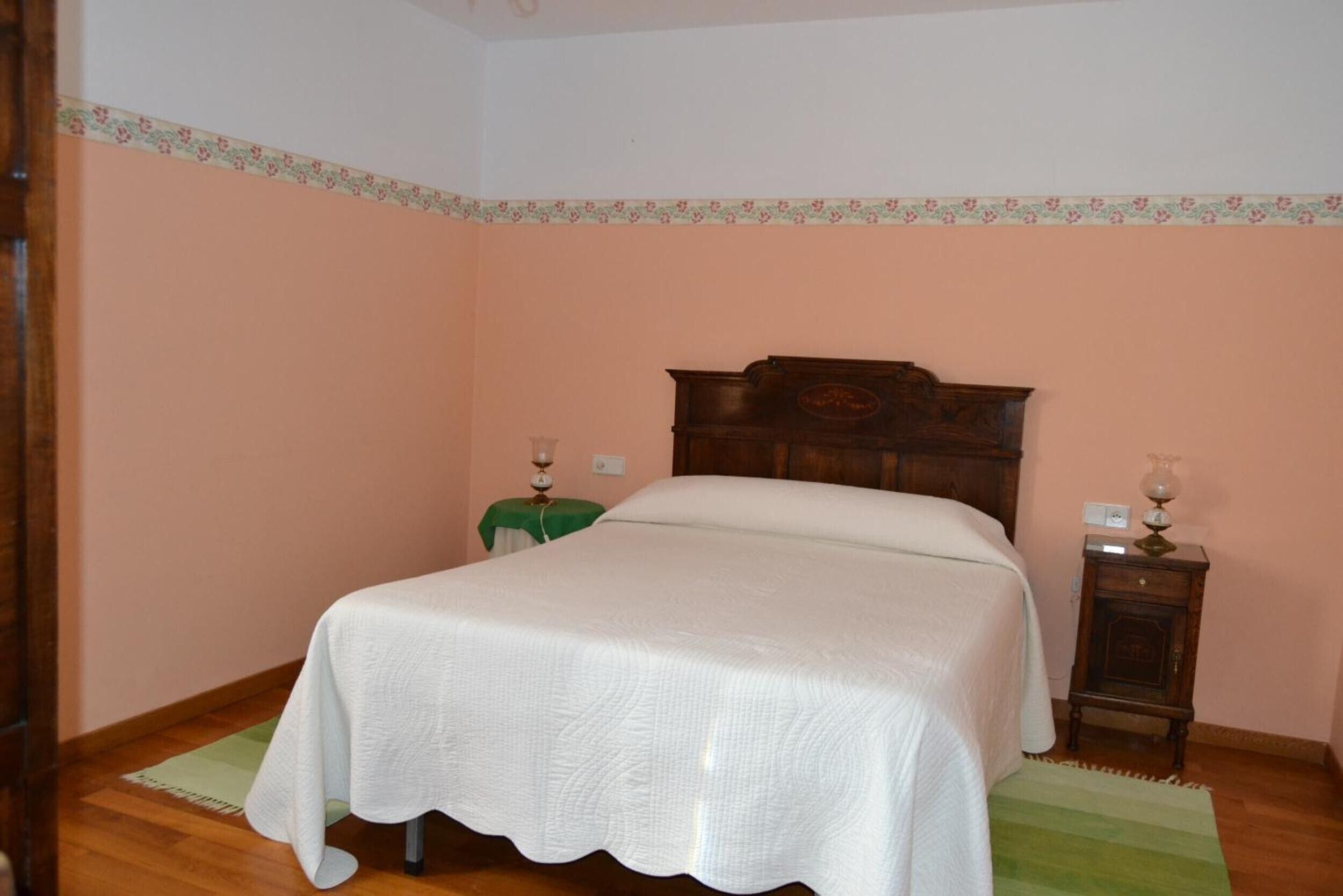 Une chambre à coucher avec un lit en bois, une chaise verte, une table de chevet et un tapis vert.