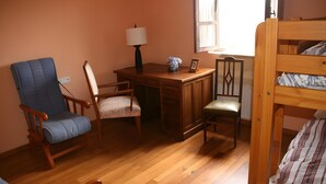 Une pièce avec un bureau en bois, une chaise, un lit et une fenêtre.