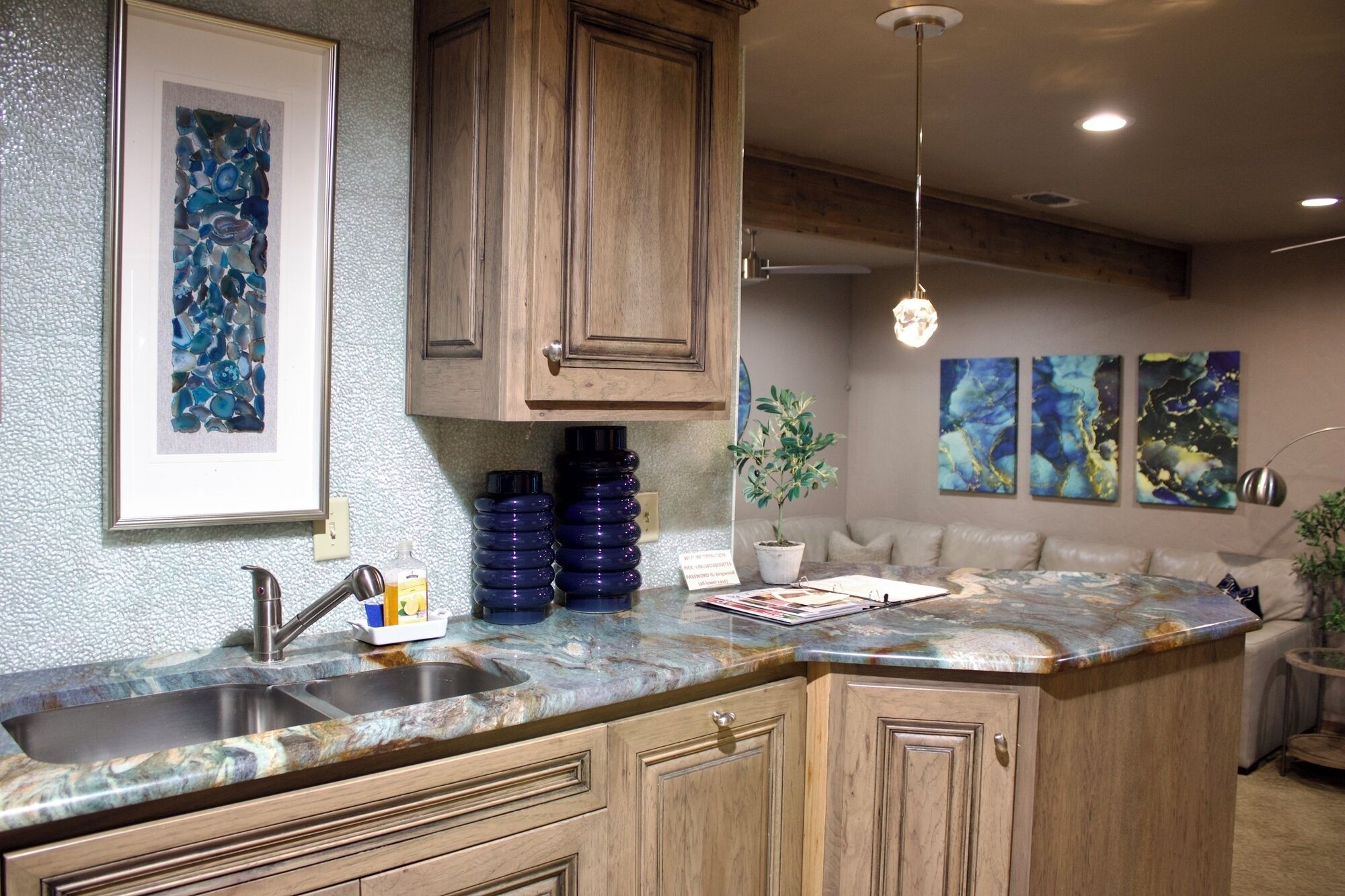A kitchen with a marble countertop, wooden cabinets, a sink, and a hanging pendant light.