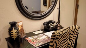 Un bureau avec un miroir, une lampe, un téléphone et une chaise dotée d’un coussin à motifs zébrés.