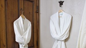 Deux robes blanches sont suspendues à des portes en bois dans une salle de bain.