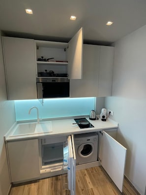 A compact kitchen with a built-in washing machine, a sink, and a countertop with a kettle and a coffee maker. - Fisch house (Chioggia)