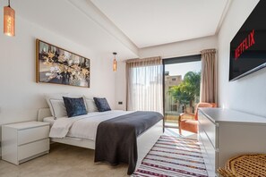 A modern bedroom with a bed, a TV, a balcony with a view, and a painting on the wall. - Palais Arbaa (Marrakech)