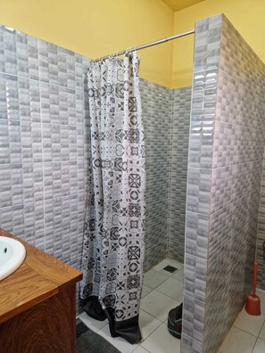 Une salle de bain avec un rideau de douche, un lavabo et des toilettes.