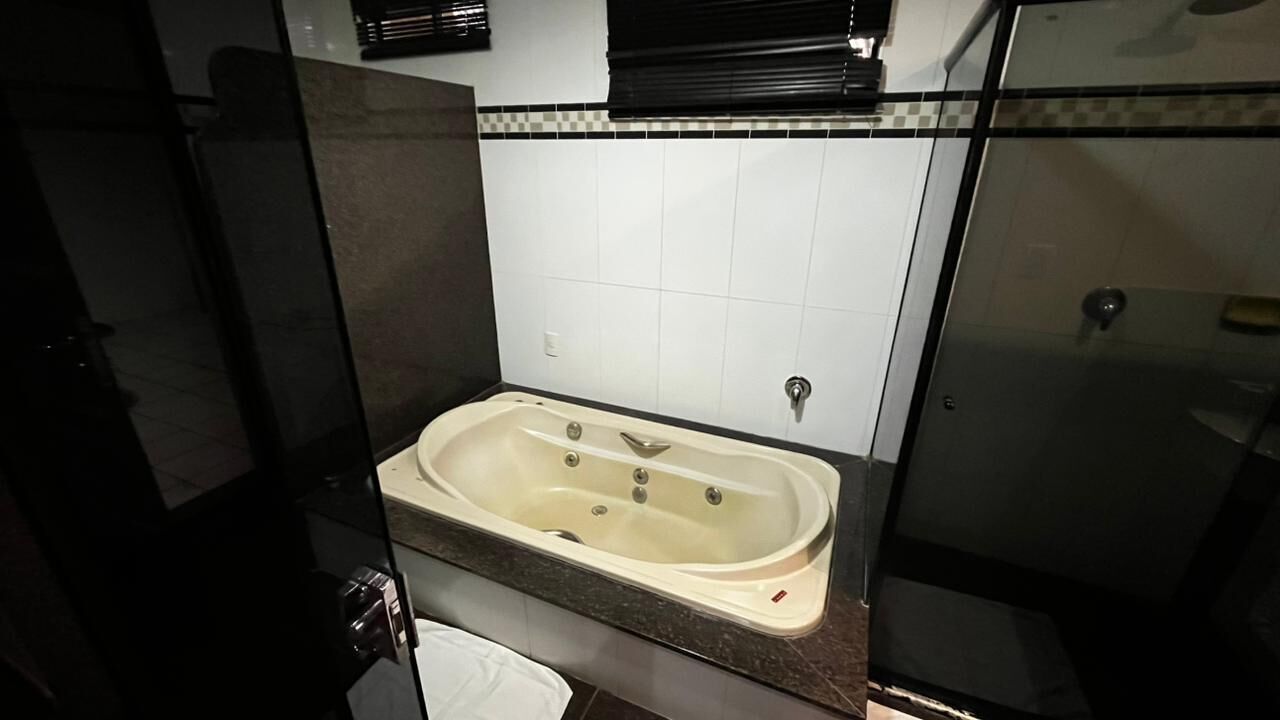 Un baño con bañera, inodoro y mampara de vidrio.