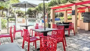 Terrasse mit Tischen, Stühlen, Sonnenschirmen und einer Pergola.
