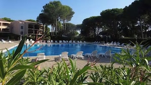 Ein Pool mit Liegestühlen, umgeben von Bäumen und einem Gebäude.