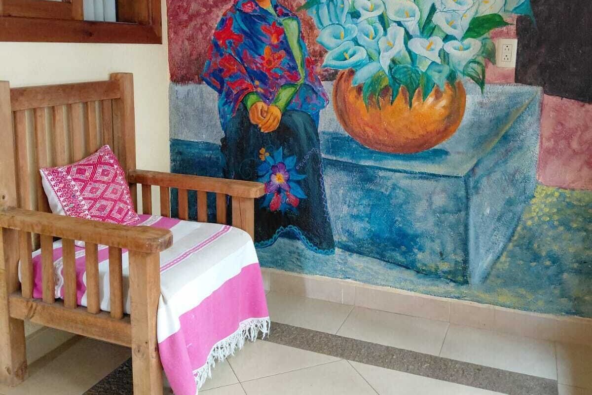 A room with a wooden chair, a large floral painting, and a tiled floor.