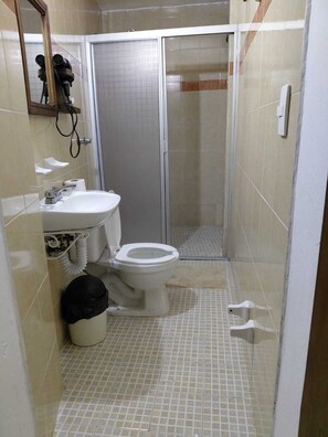 Um banheiro pequeno com vaso sanitário, pia e chuveiro.