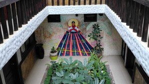 A staircase with a railing, a mural on the wall, and potted plants at the bottom. - Casa Nucu Hotel (San Cristóbal de las Casas)